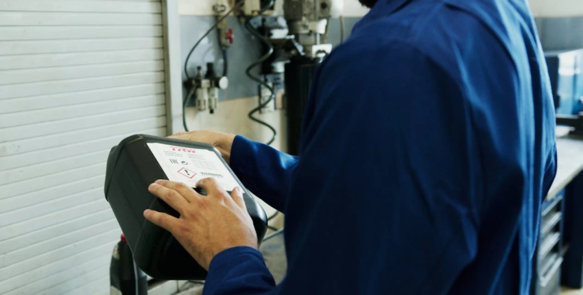 Technician performing an oil change with diagnostic equipment in an auto shop.