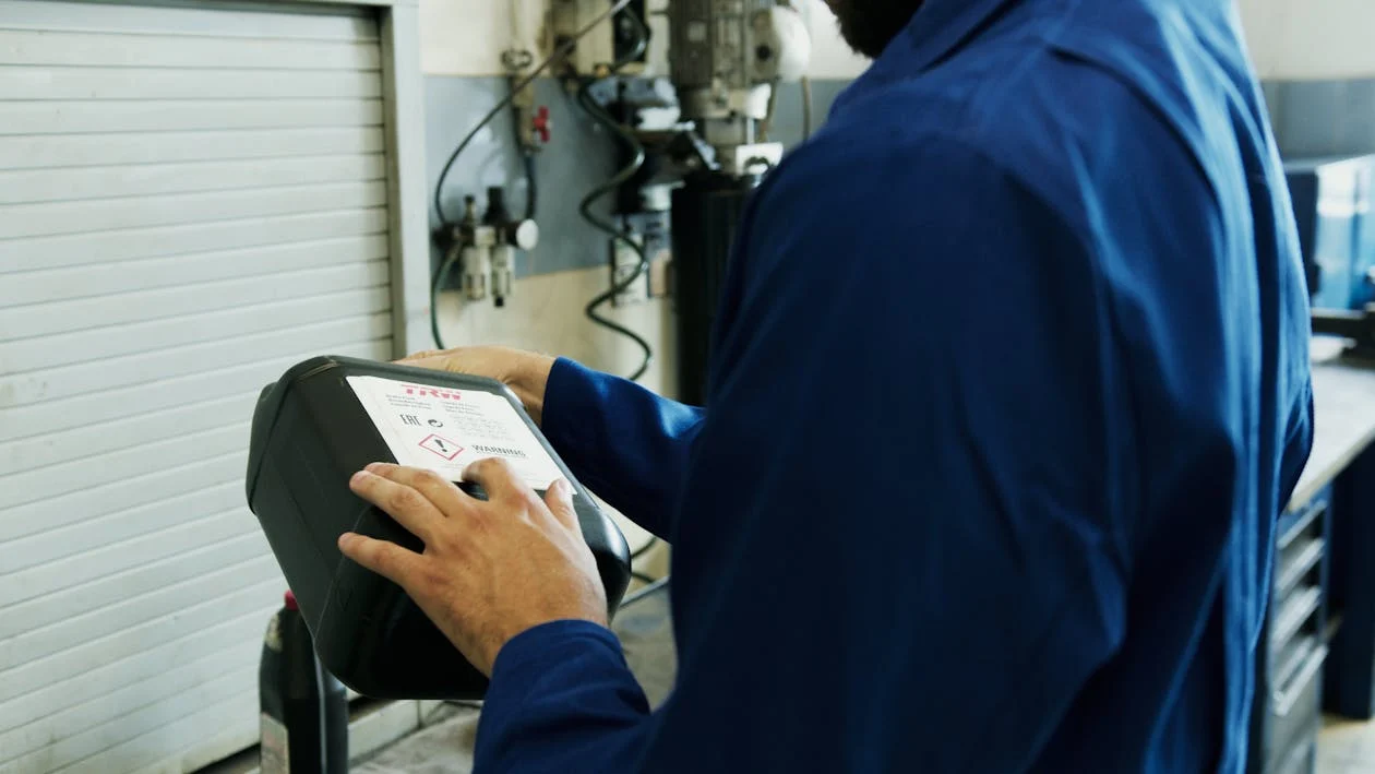 Technician performing an oil change with diagnostic equipment in an auto shop.