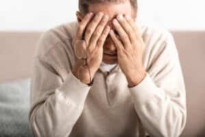 Distressed man has his lands covering his eyes. Sad / worried / upset.