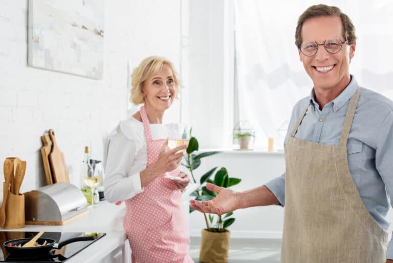 Happy old man in apron and eyeglasses smiling at camera
