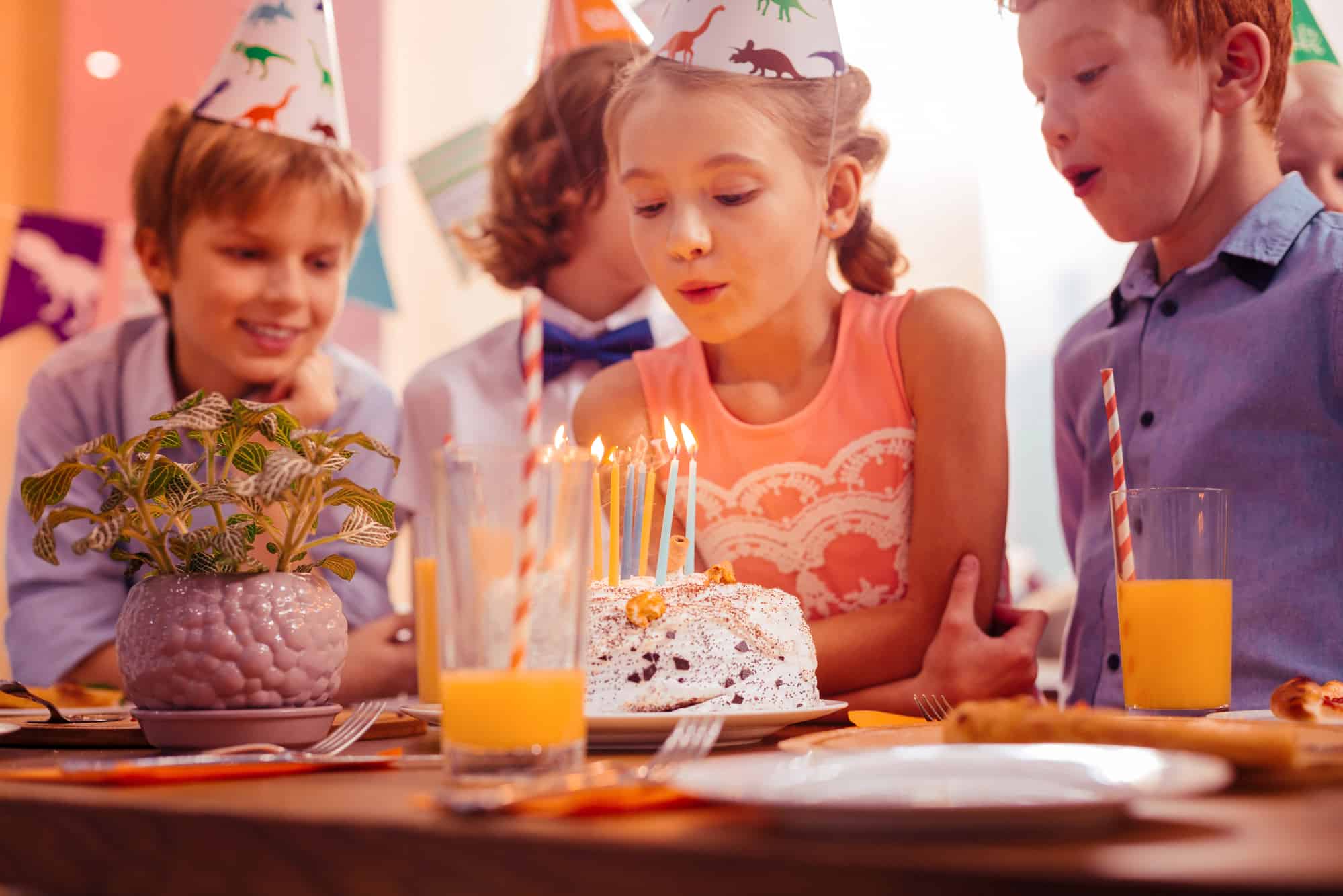 Keep smiling. Attentive girl leaning on table while blowing candles