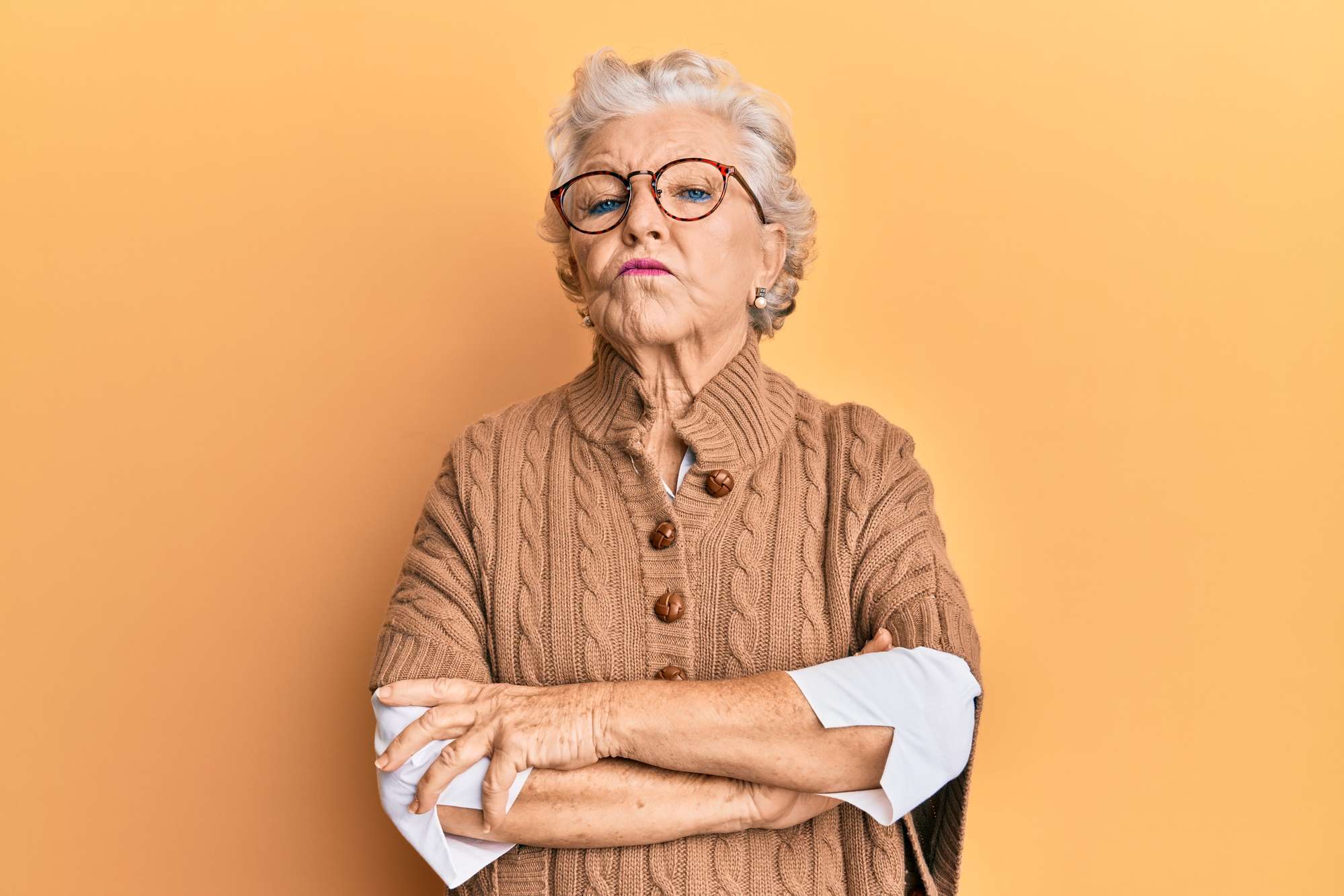 Senior grey-haired woman wearing casual clothes and glasses skeptic and nervous, disapproving expression on face with crossed arms. negative person. Old. Angry / upset.
