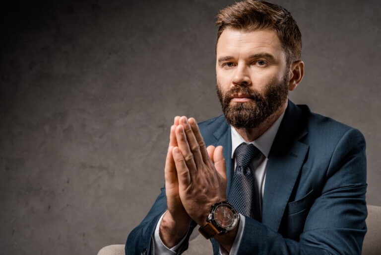 Close up of bearded businessman sitting in armchair with praying hands 