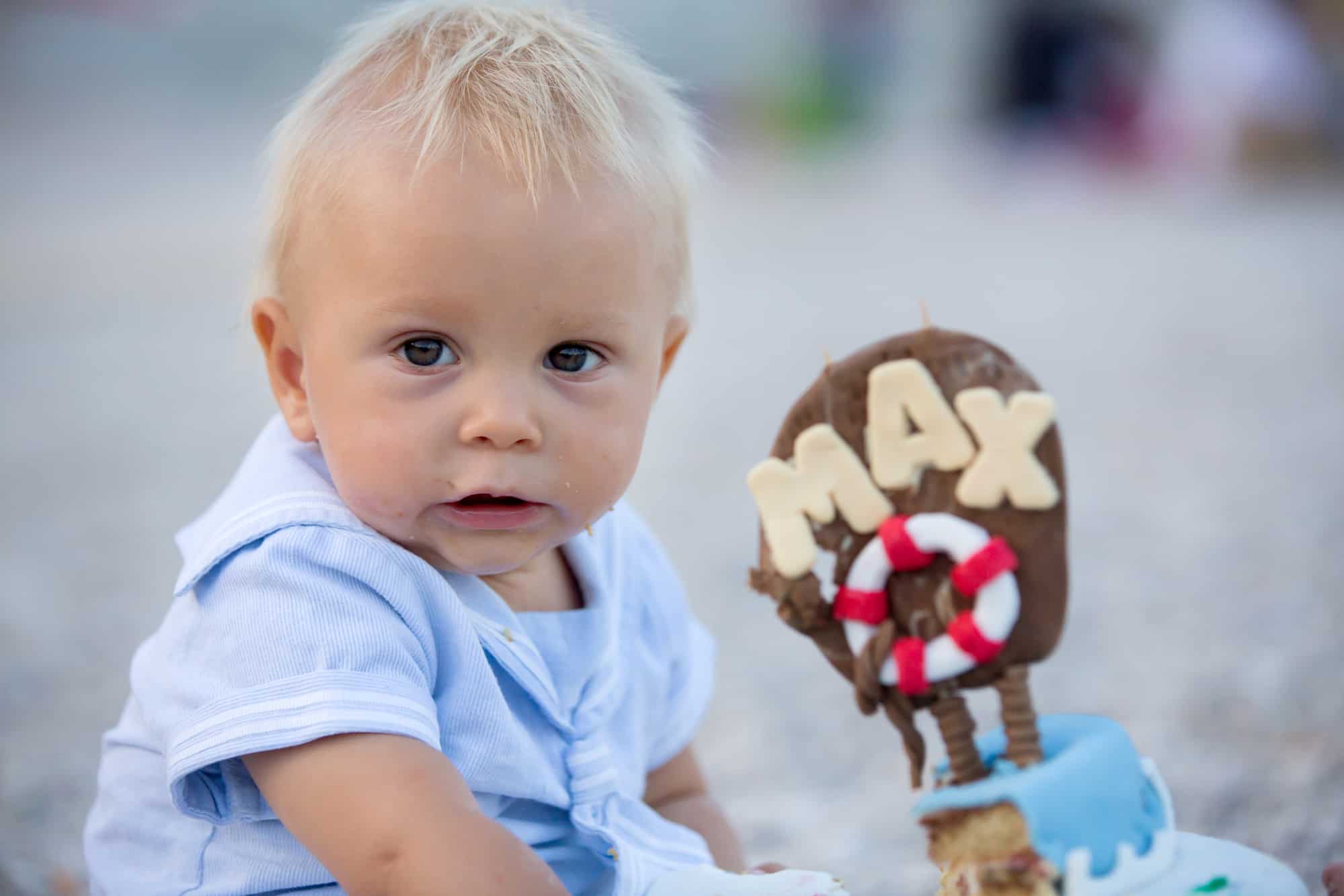 Sweet baby boy, celebrating on the beach first birthday with sea theme cake and sea decoration.