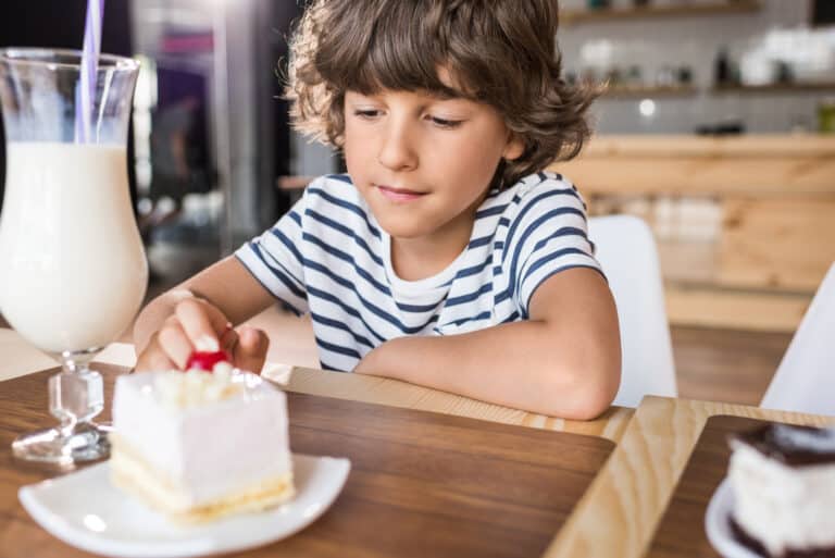 Boy with piece of cake in cafe