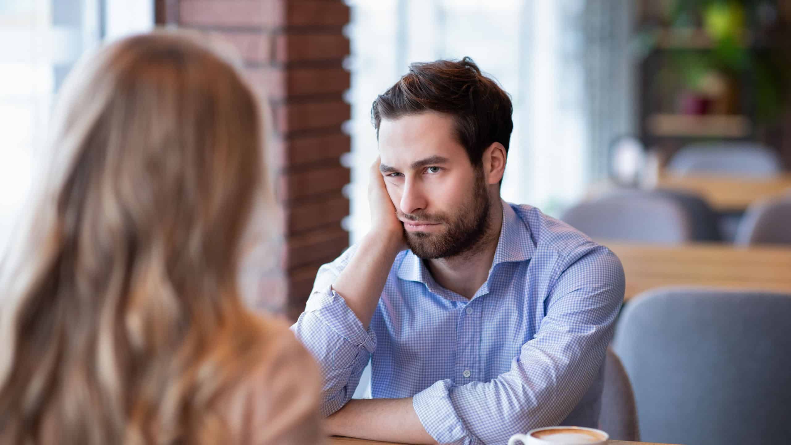 Young guy feeling bored on dull date at restaurant, disappointed in his partner. Millennial couple having disagreement, cannot find common grounds. Relationship problem concept
