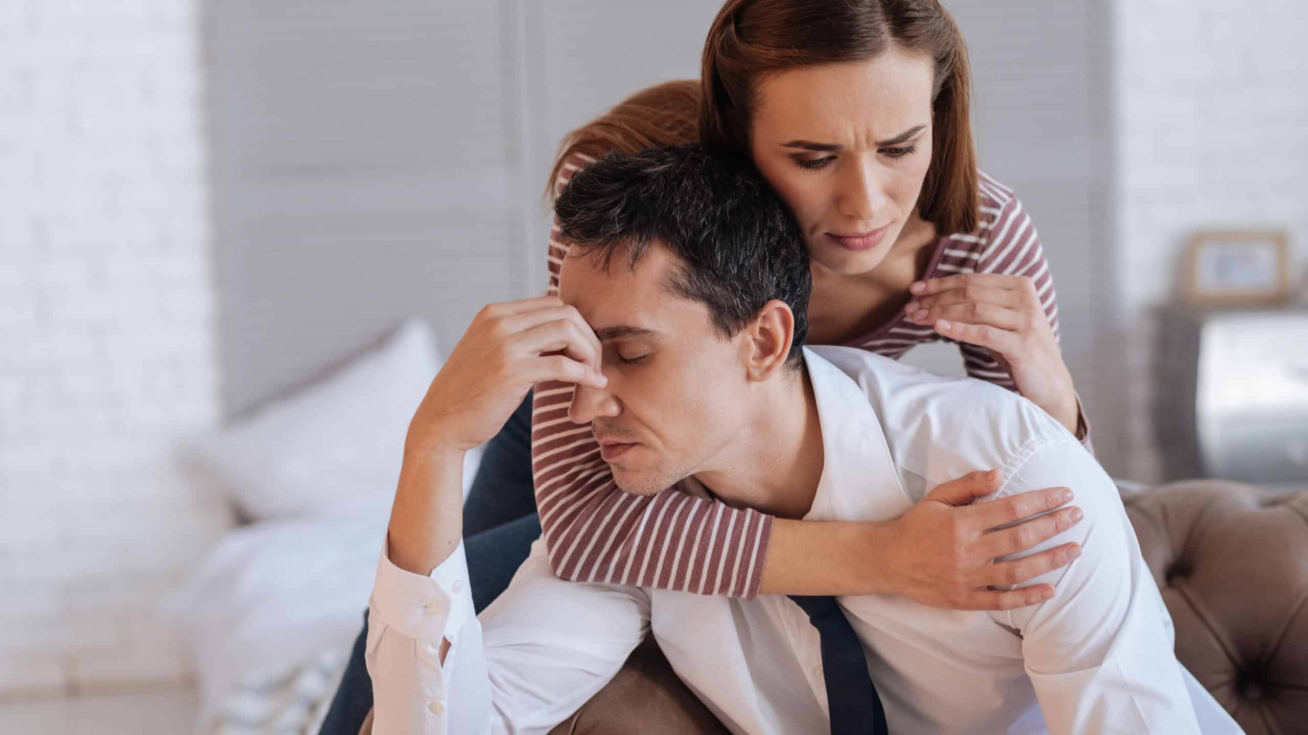 Warm hugs. Cheerful kind loving woman looking friendly and supporting while hugging her depressed exhausted husband