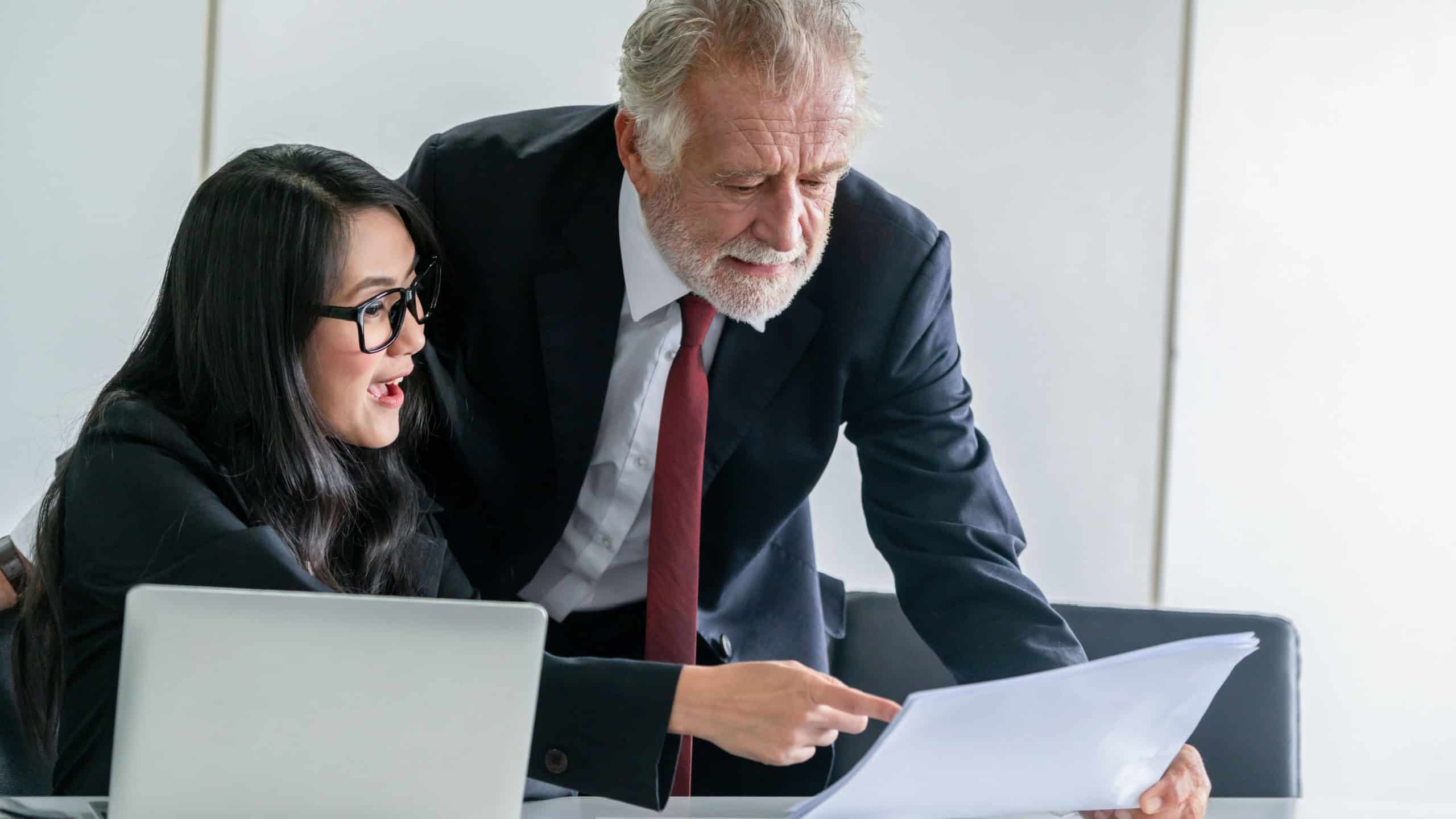 Senior executive manager and young businesswoman working in meeting room in the office. The woman is secretary or translator. International business language translation concept.