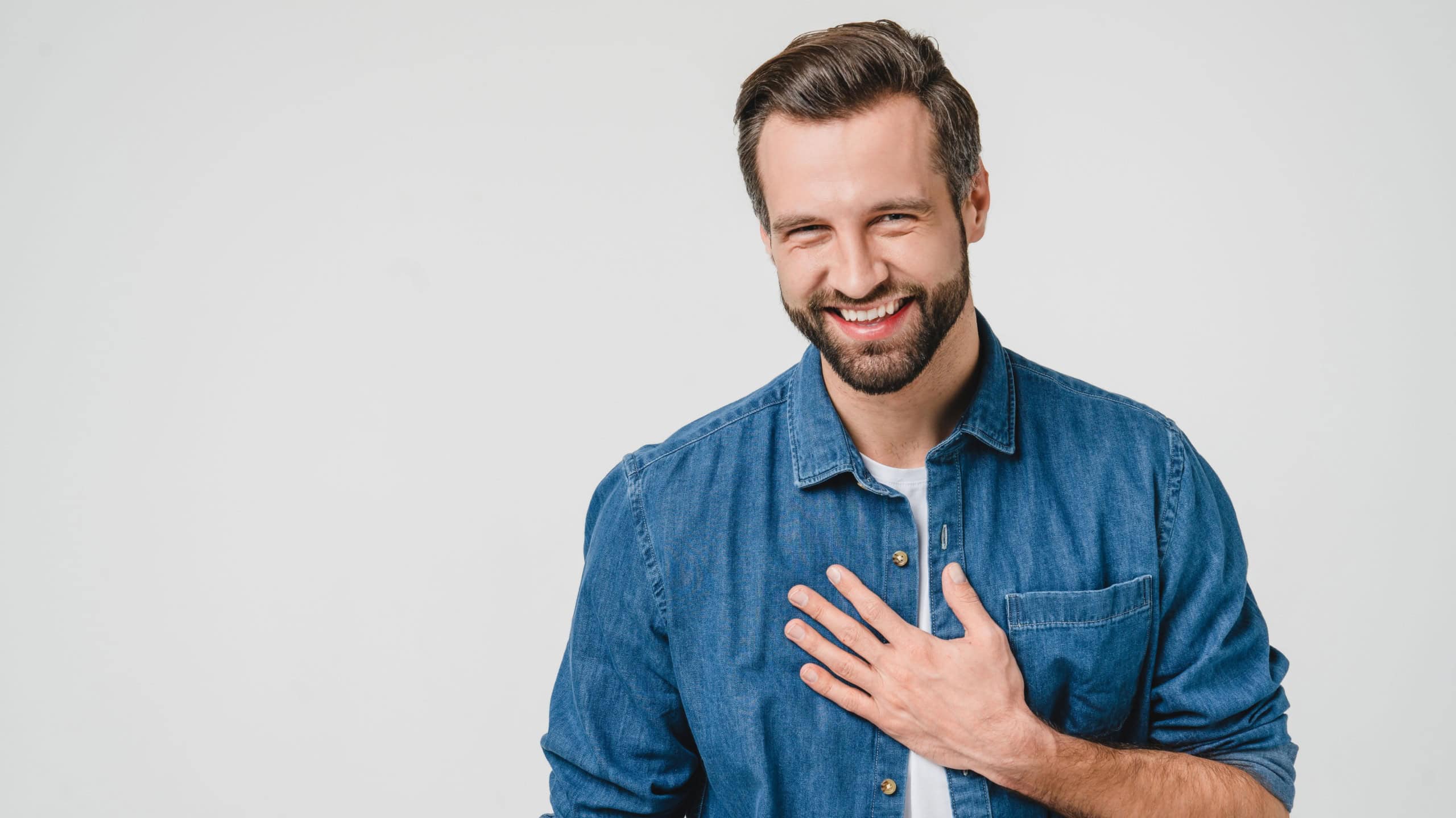 Happy young caucasian man in denim clothes laughing, touched with a compliment, good sense of humor isolated in white background