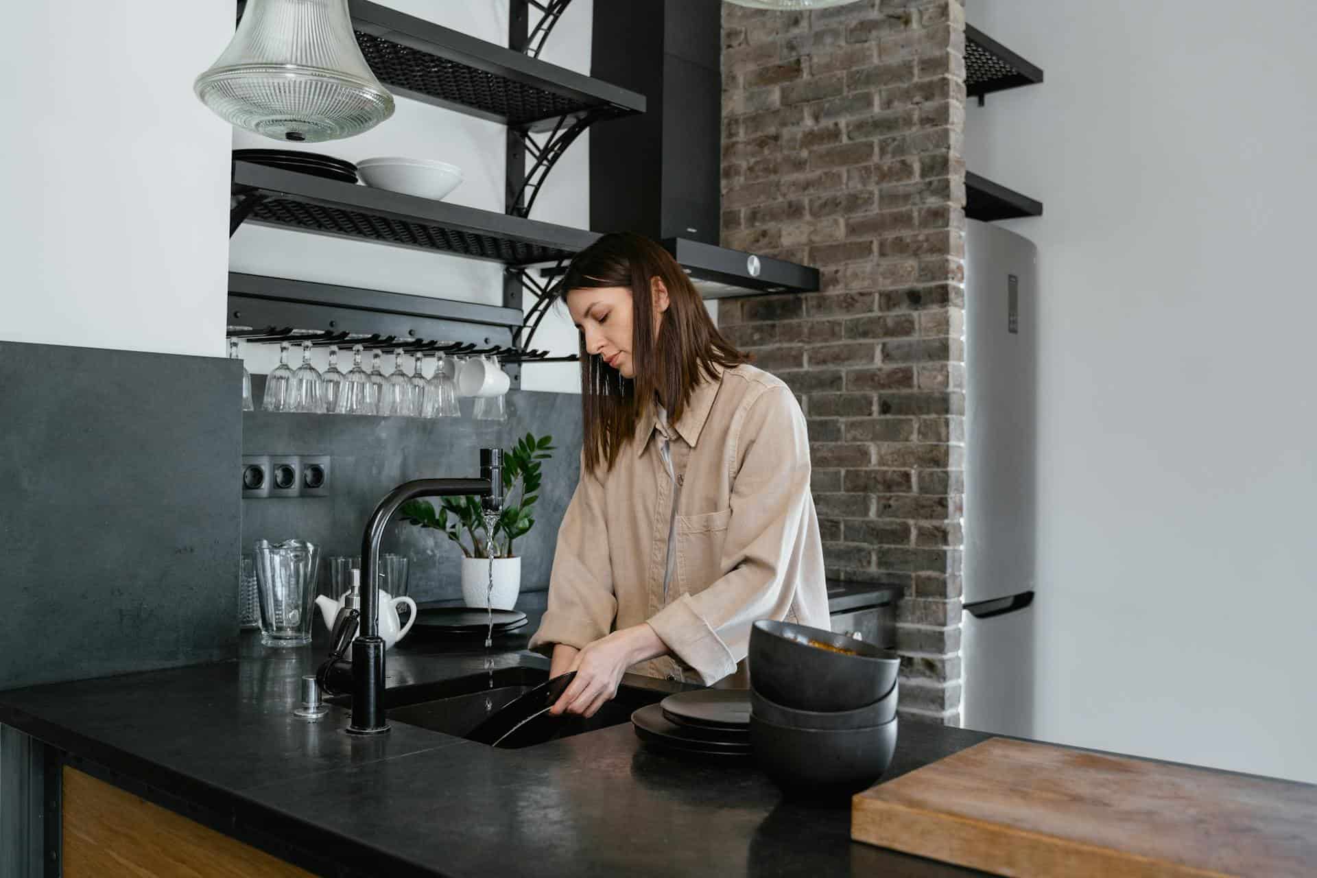 A Woman Washing Dishes in the Kitchen Sink