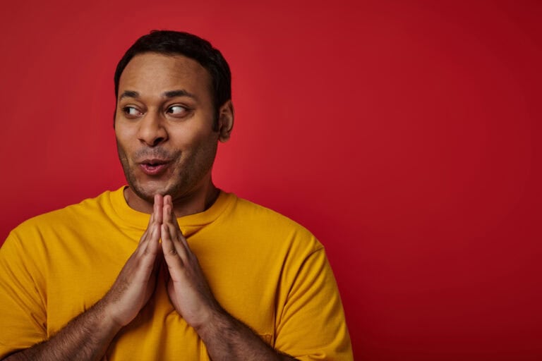 Cunning indian man in yellow t-shirt clasping hands