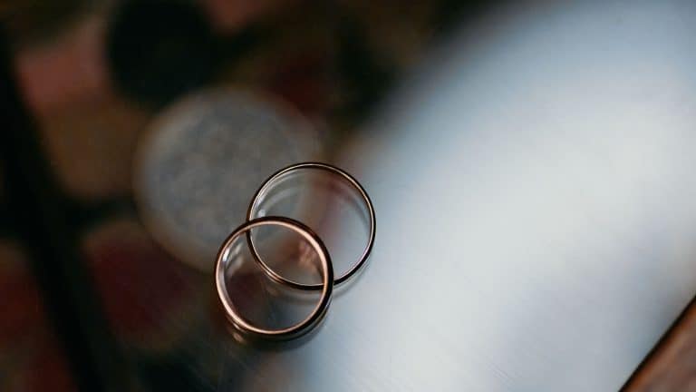 Two gold wedding rings placed together on a glass surface symbolize love, unity, and commitment. The minimalist setup highlights the symbolic nature of marriage and togetherness.