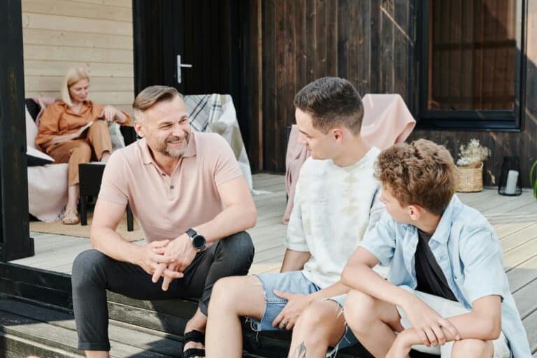 Happy Family Sitting Together in front of House