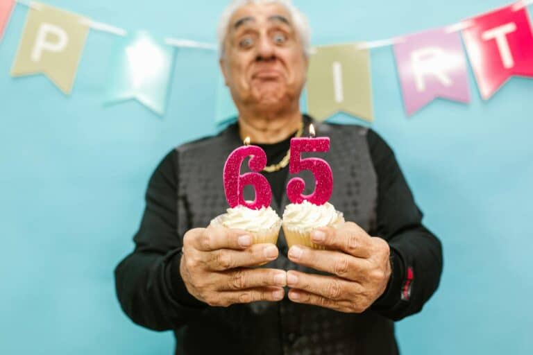 Senior Man Holding Cupcakes With Lit Candles - 65th Birthday