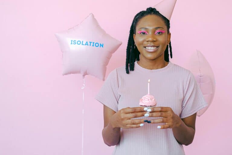 A Woman Holding a Cupcake with Lighted Candles on Top while Smiling at the Camera