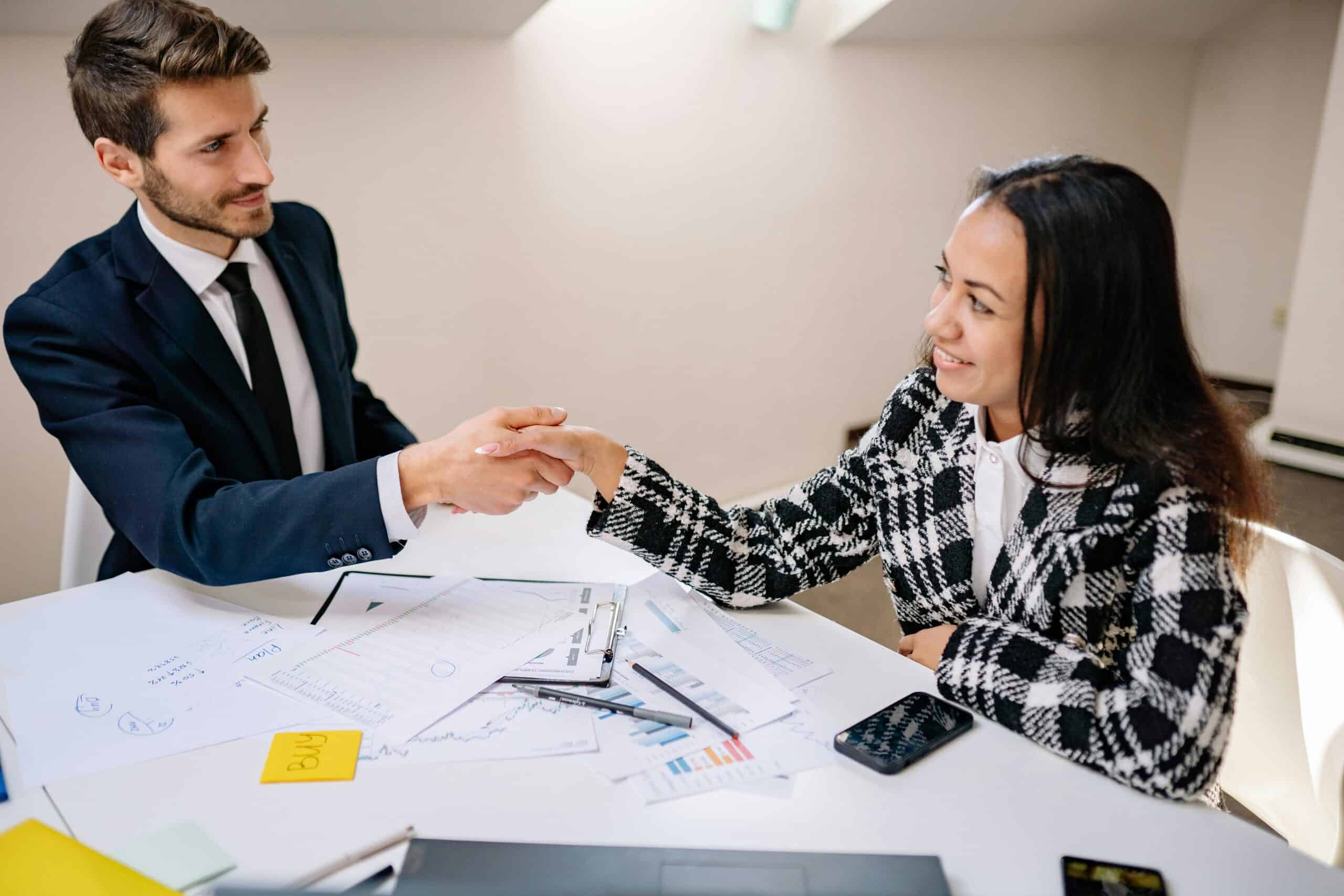 Man and Woman Sitting at the table and shaking hands while smiling