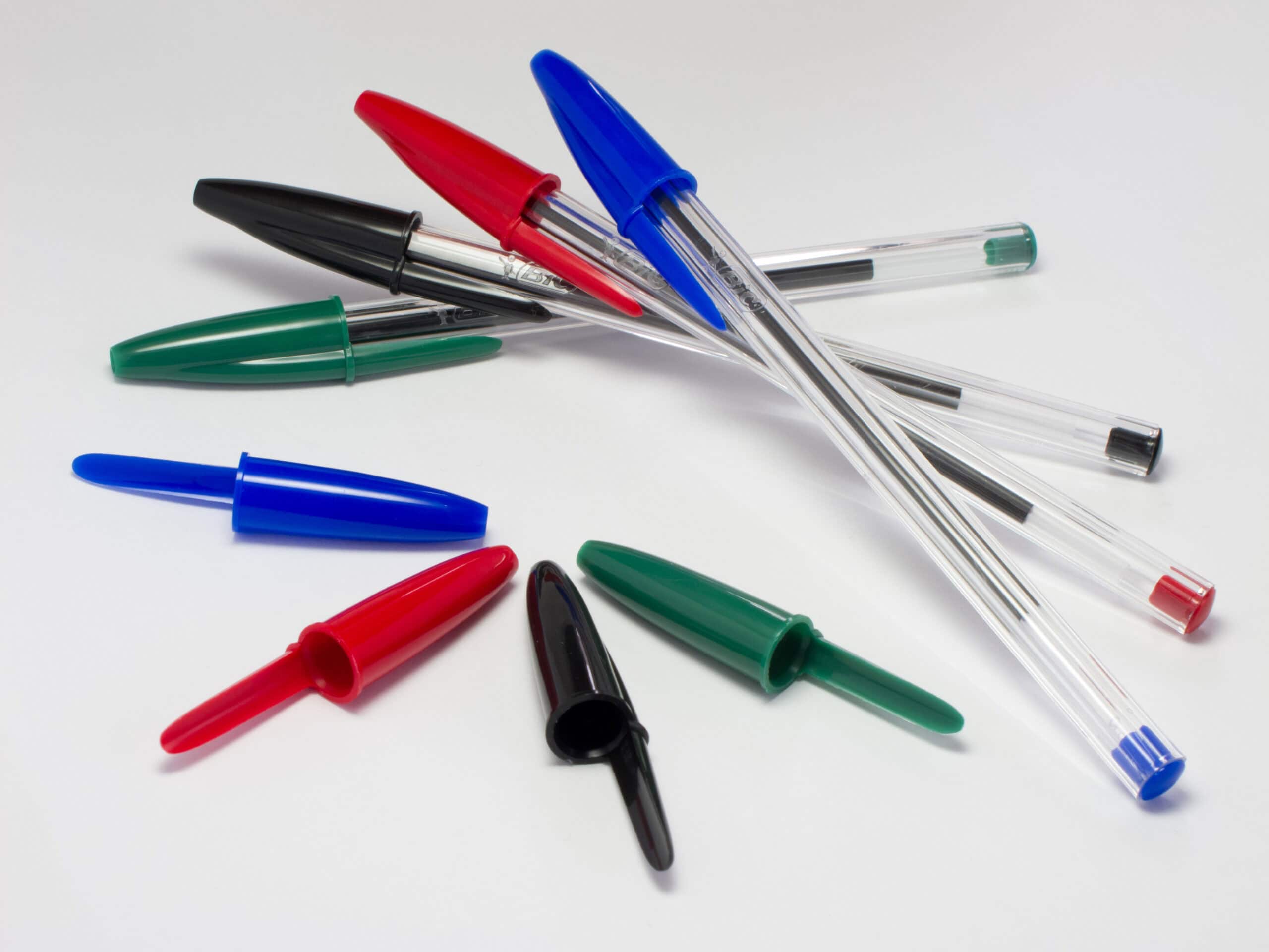 Four blue, red, black and green BIC pens and four pen caps