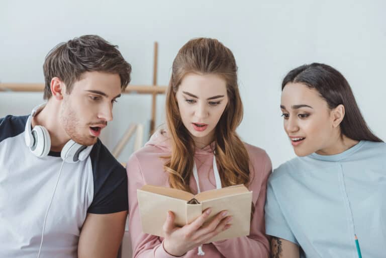 Shocked young students reading one book