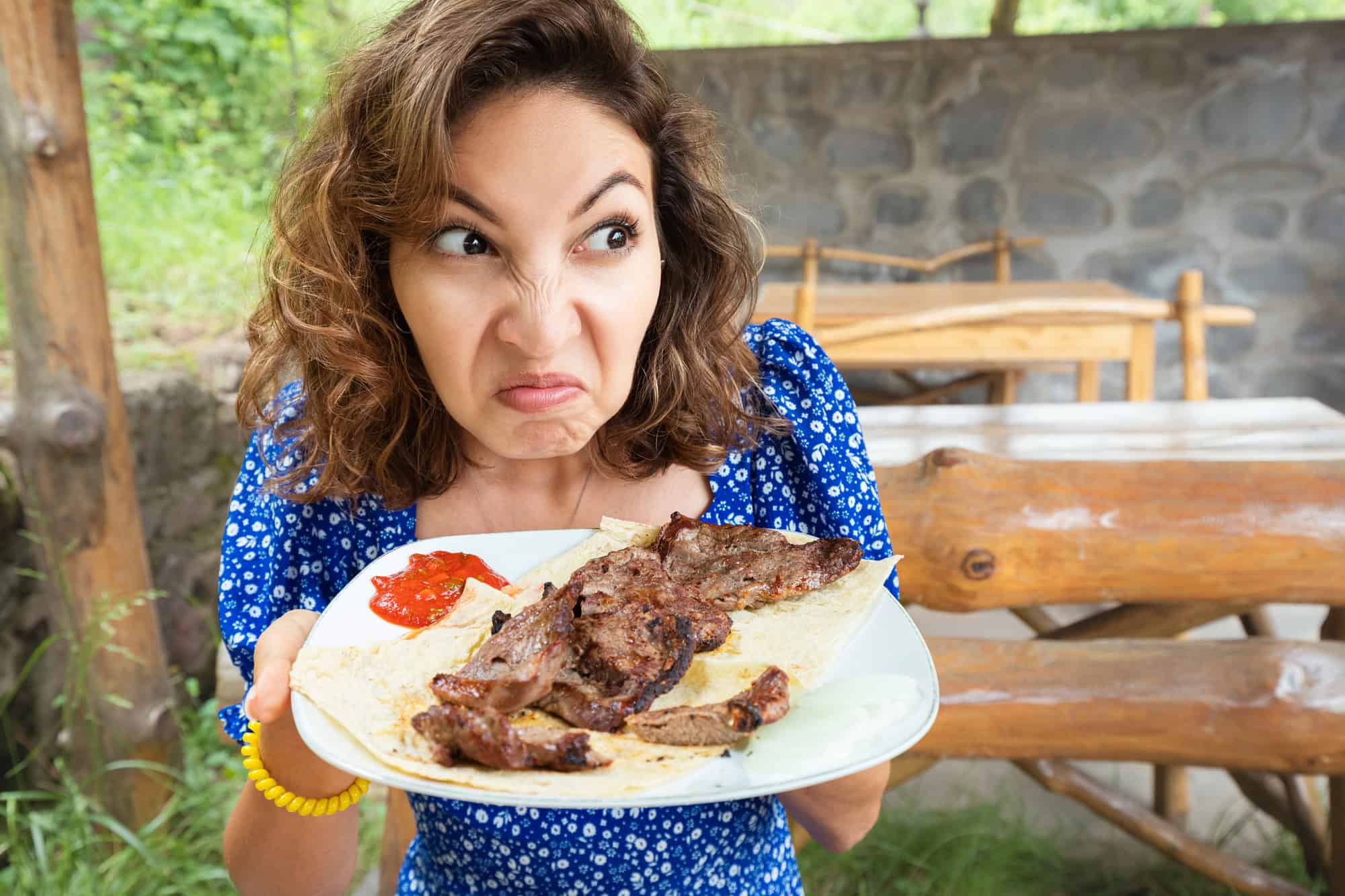 Remove BG Save Share Sample Woman sniffs a spoiled steak in a restaurant.