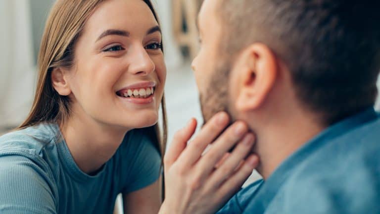 Excited young woman smiling happily and touching a cheek of her boyfriend stock photo