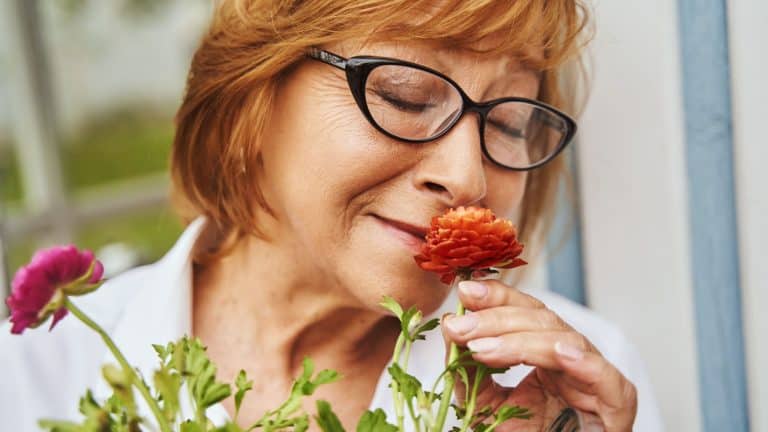 Happy mature female smelling flowers in countryside