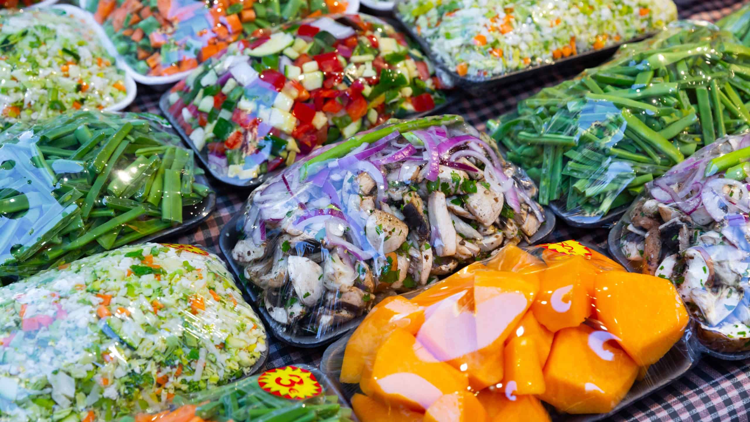 Mixed cut vegetables packed in plastic containers for sale in grocery shop.
