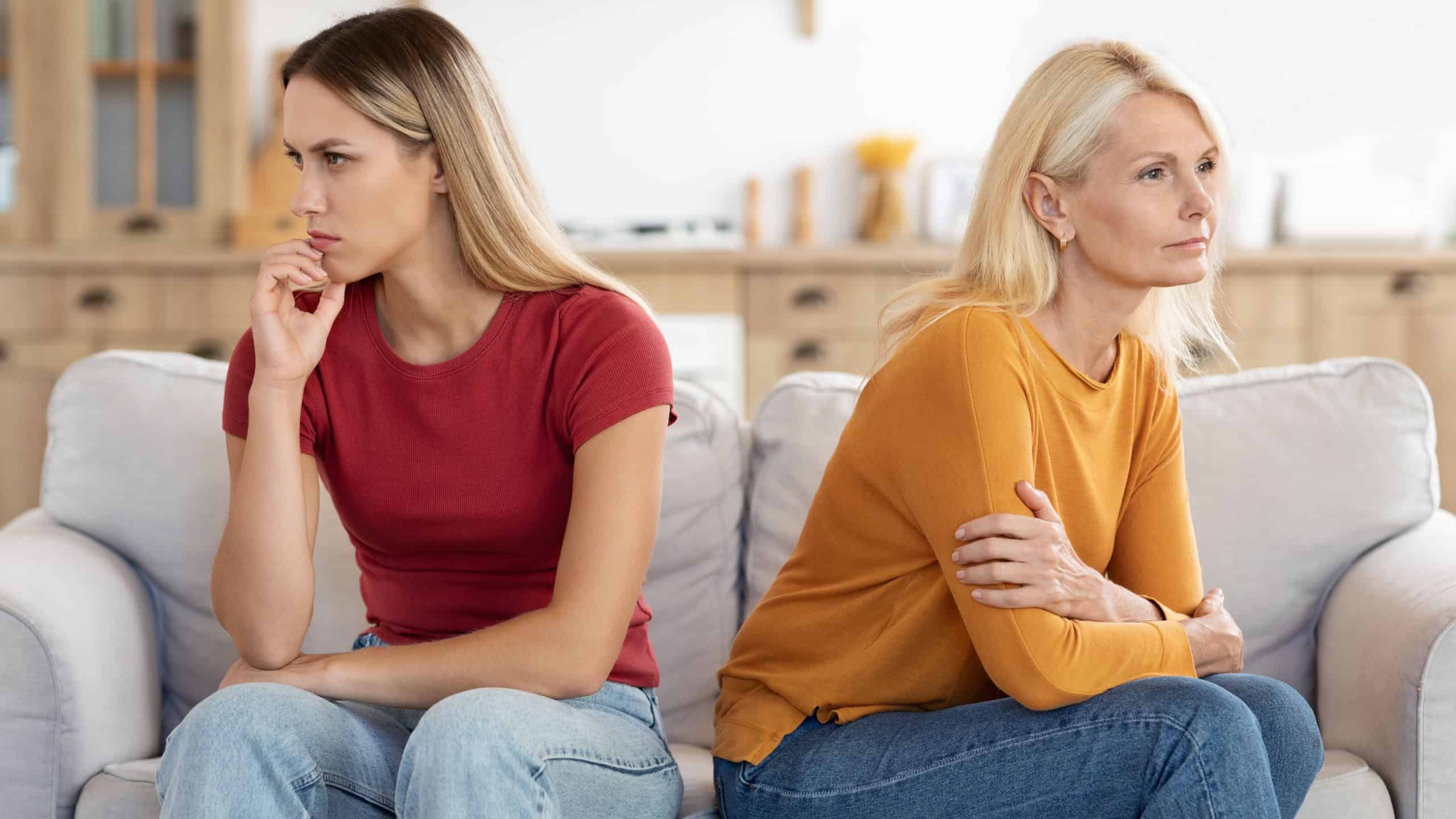 Offended millennial adult daughter and senior mother sit aside back to back avoid talking after fight, hurt stubborn two generations women ignore each other after conflict, misunderstanding concept