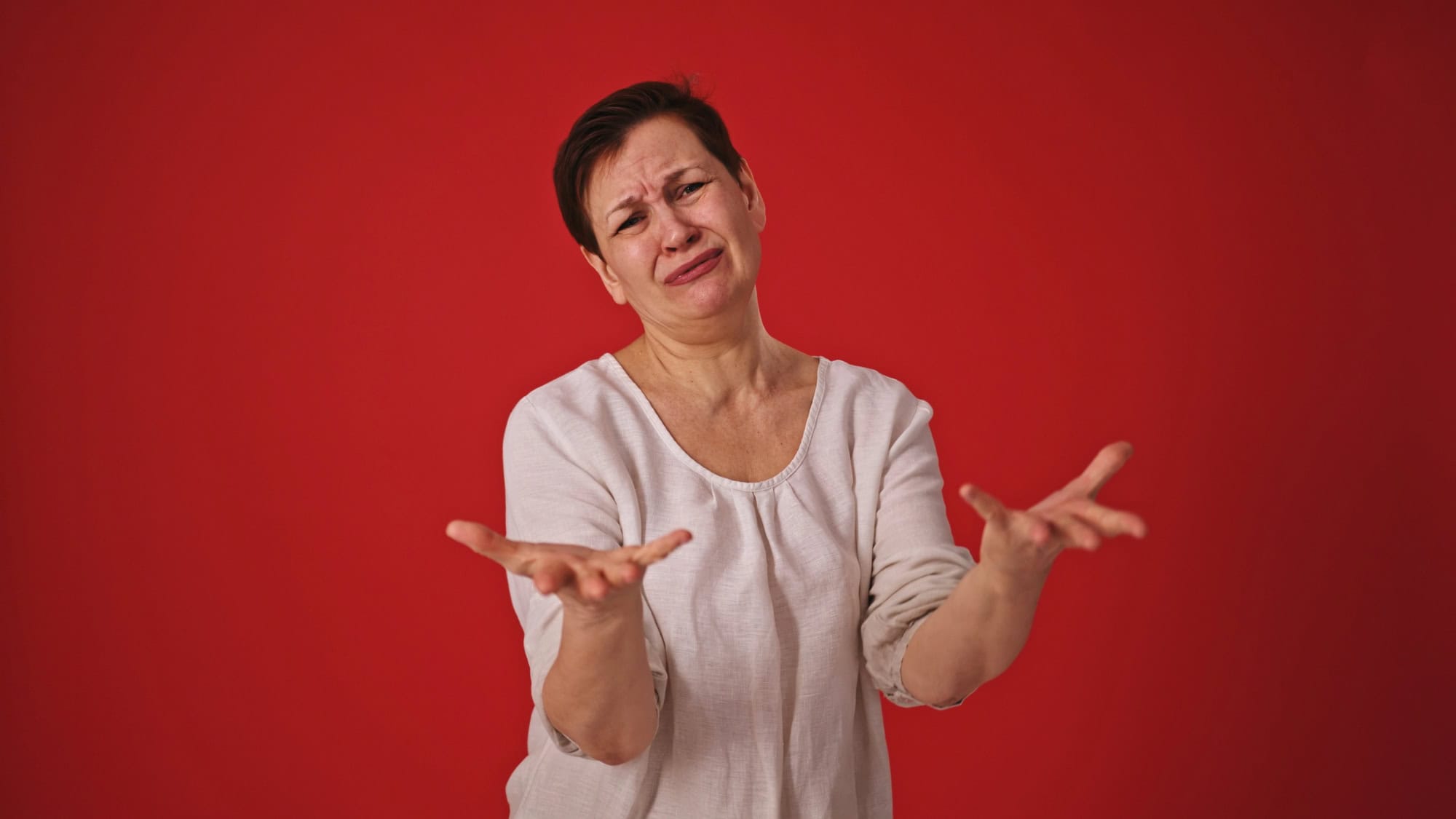 Mature Woman Yelling and Gesturing Wildly on Red Background. High quality 4k footage
