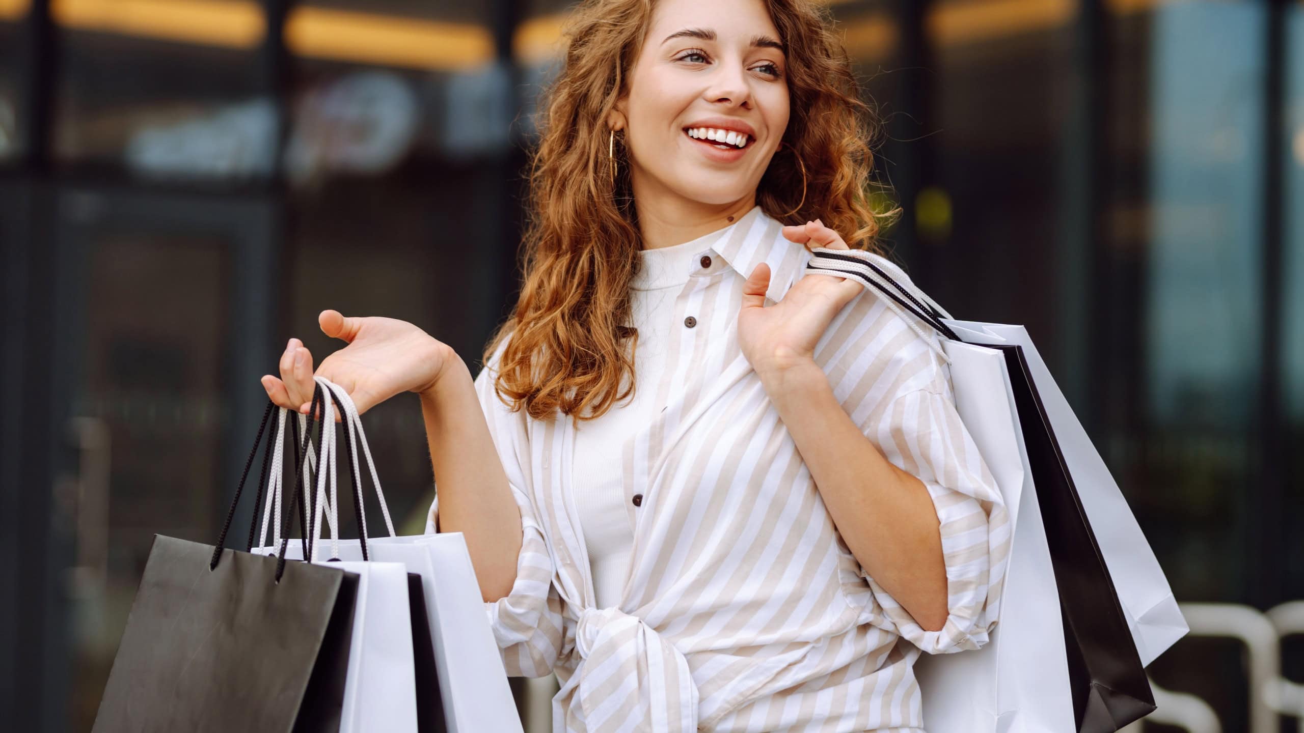 Shopping time. Young woman walking down with shopping bags on city street. Consumerism, purchases, black friday, lifestyle, sale concept.
