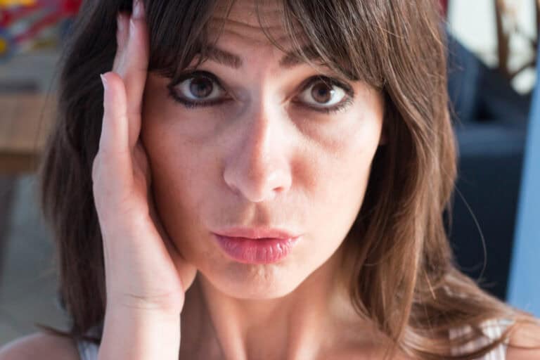 close up portrait of caucasian young woman with long hair and bangs. guilty Expression.