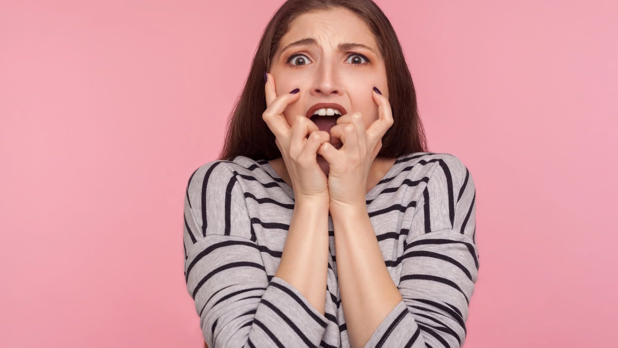 Anxiety disorder. Portrait of stressed out, nervous woman in striped sweatshirt biting nails, neurotic person looking scared, terrified of problems.