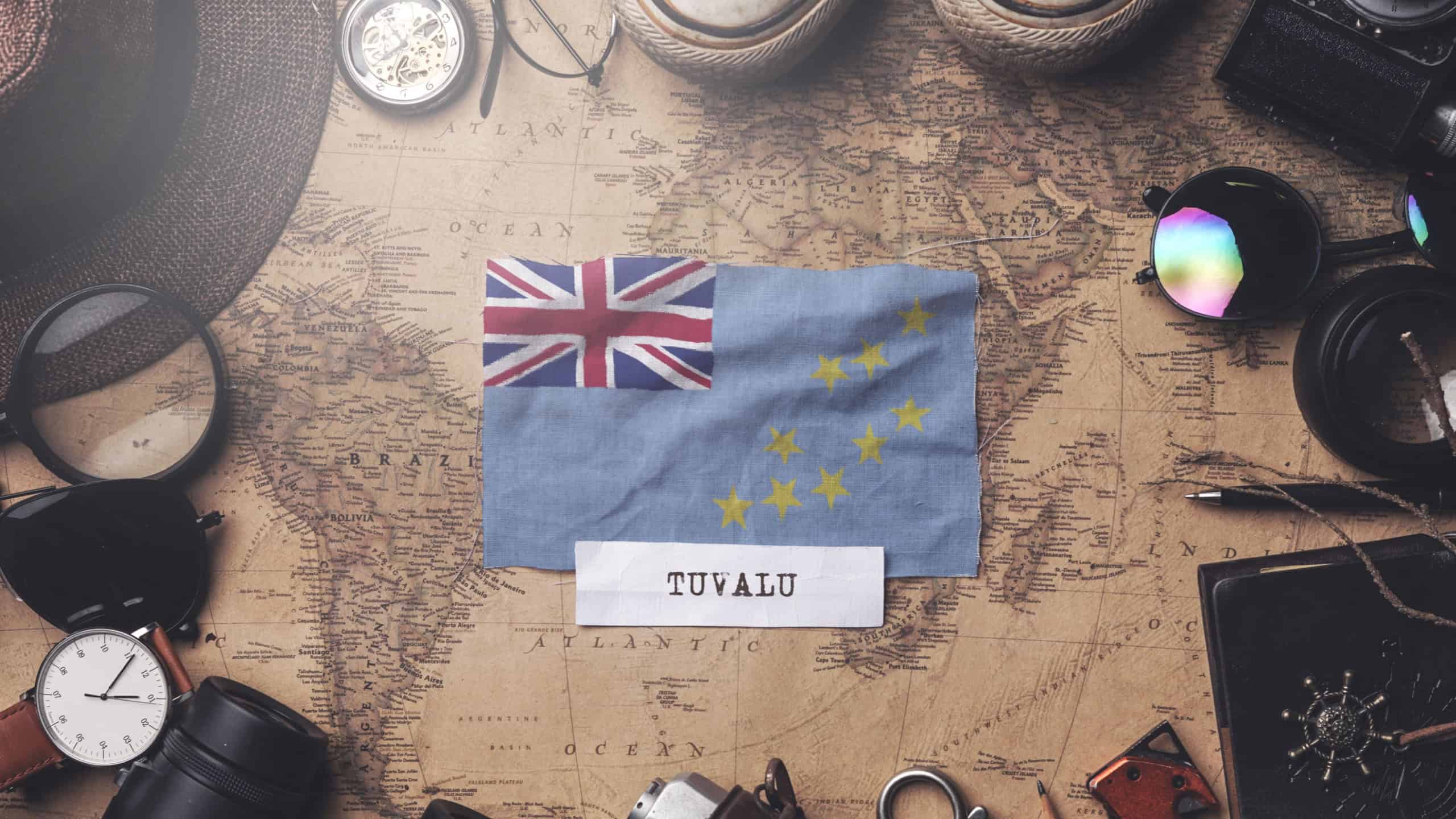 Tuvalu Flag Between Traveler's Accessories on Old Vintage Map. Overhead Shot