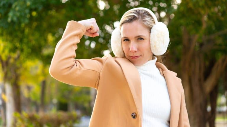 Young blonde woman wearing winter muffs at outdoors doing strong gesture