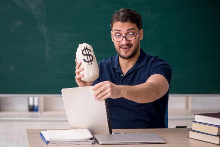 Young teacher holding moneybag in the classroom