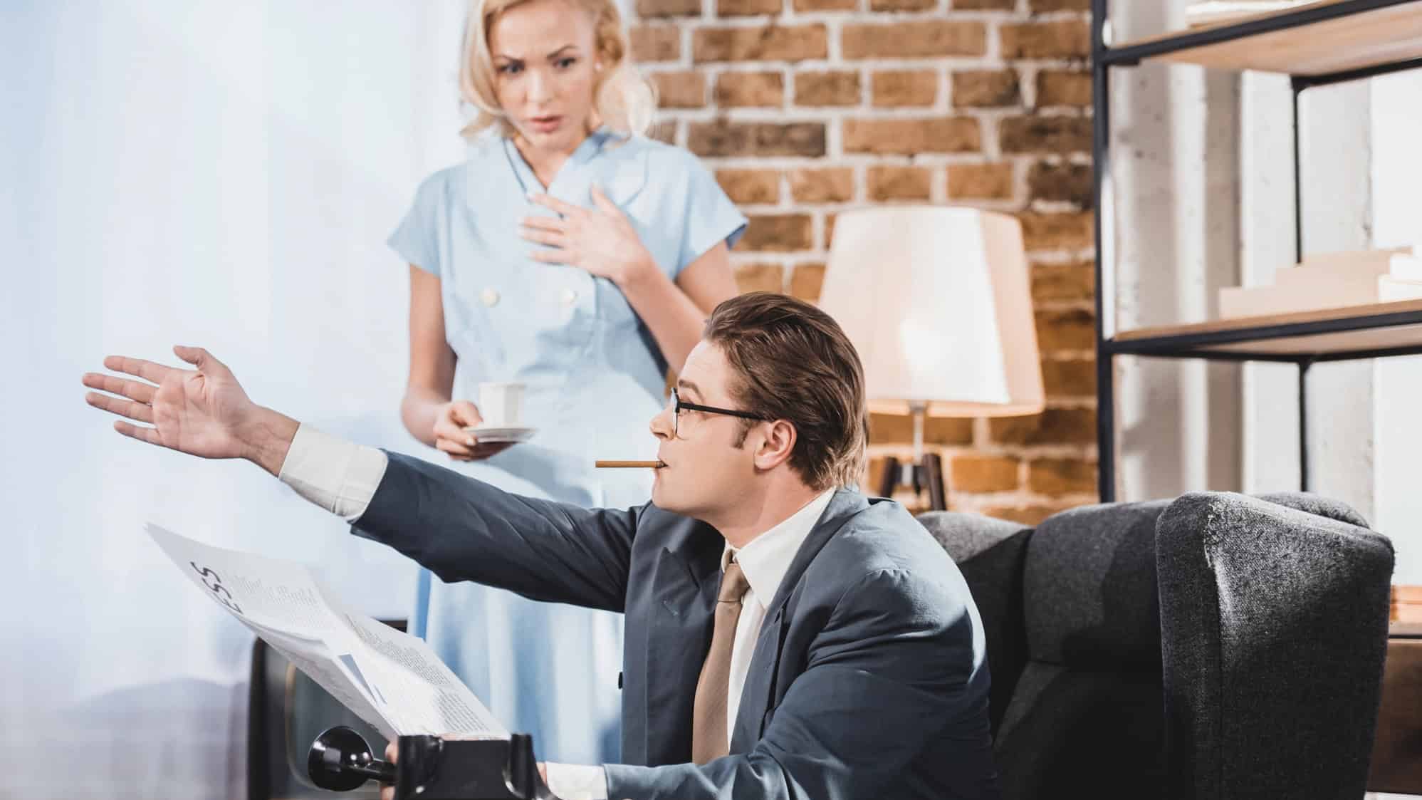 Man with cigarette reading newspaper and pointing away to upset woman holding cup of coffee, 1950s style