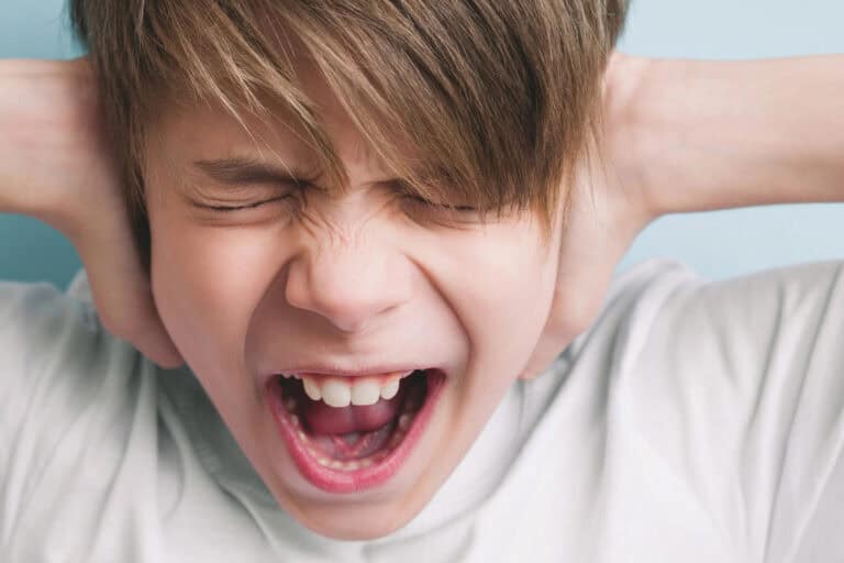 Screaming boy closes his eyes and ears in protest