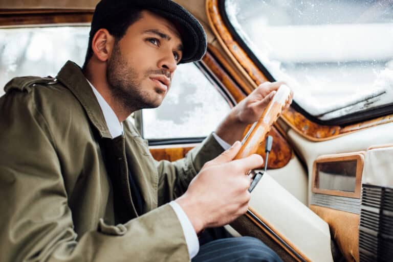 Gangster looking aside, holding steering wheel and driving car