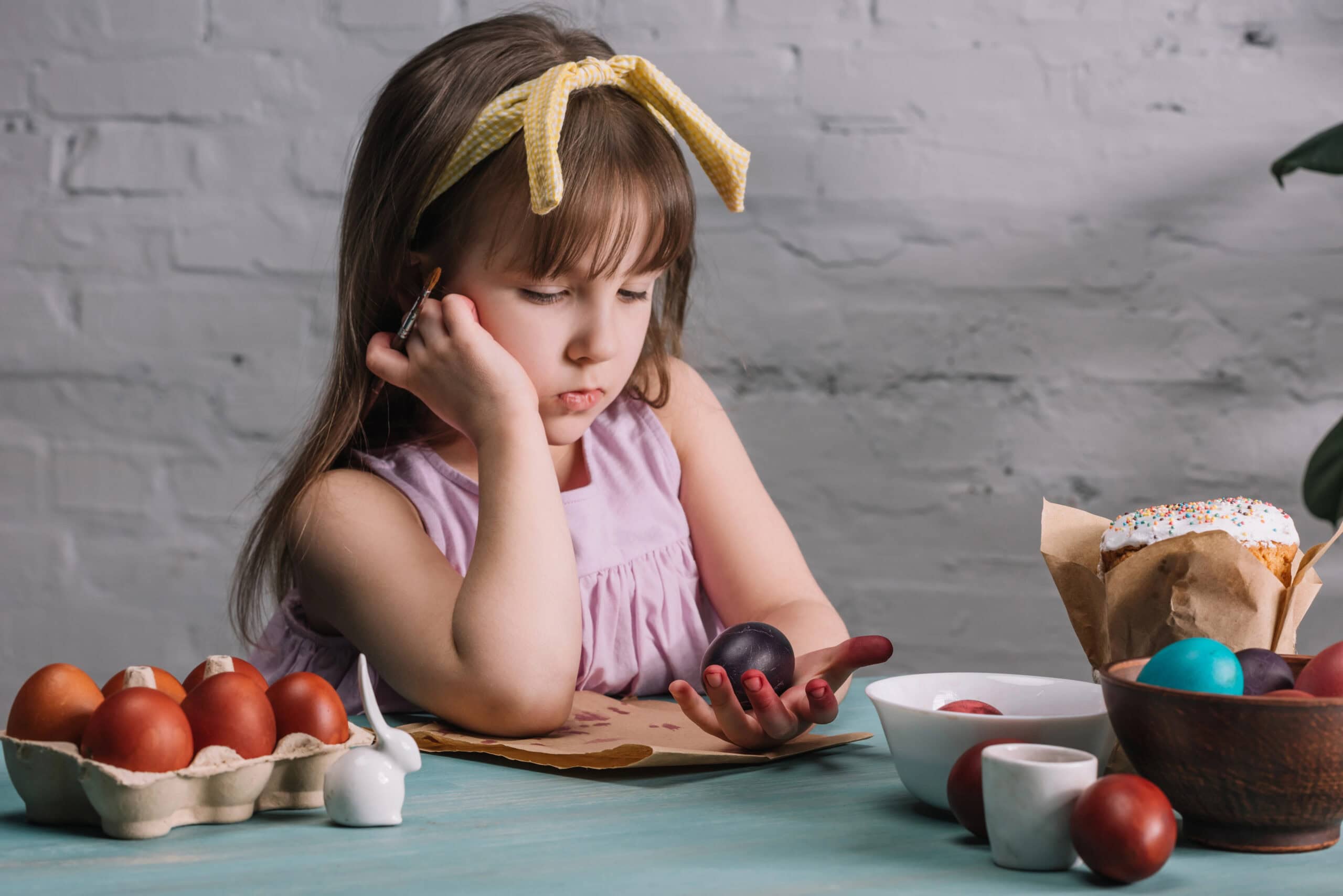 Adorable kid looking at painted easter egg in hand