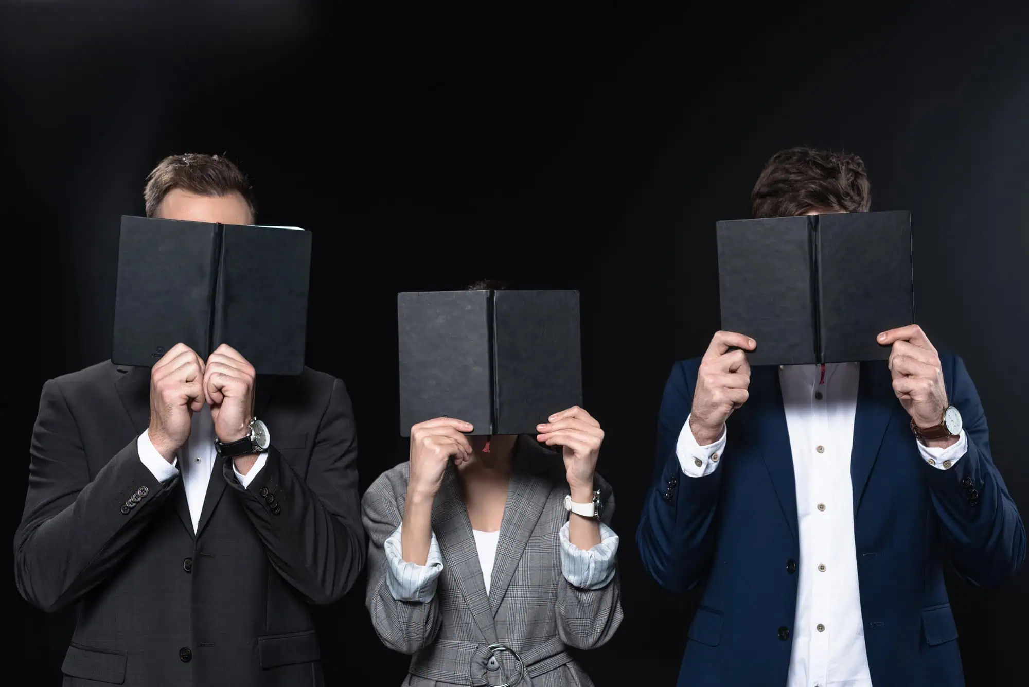 Group of business people covering faces with notebooks