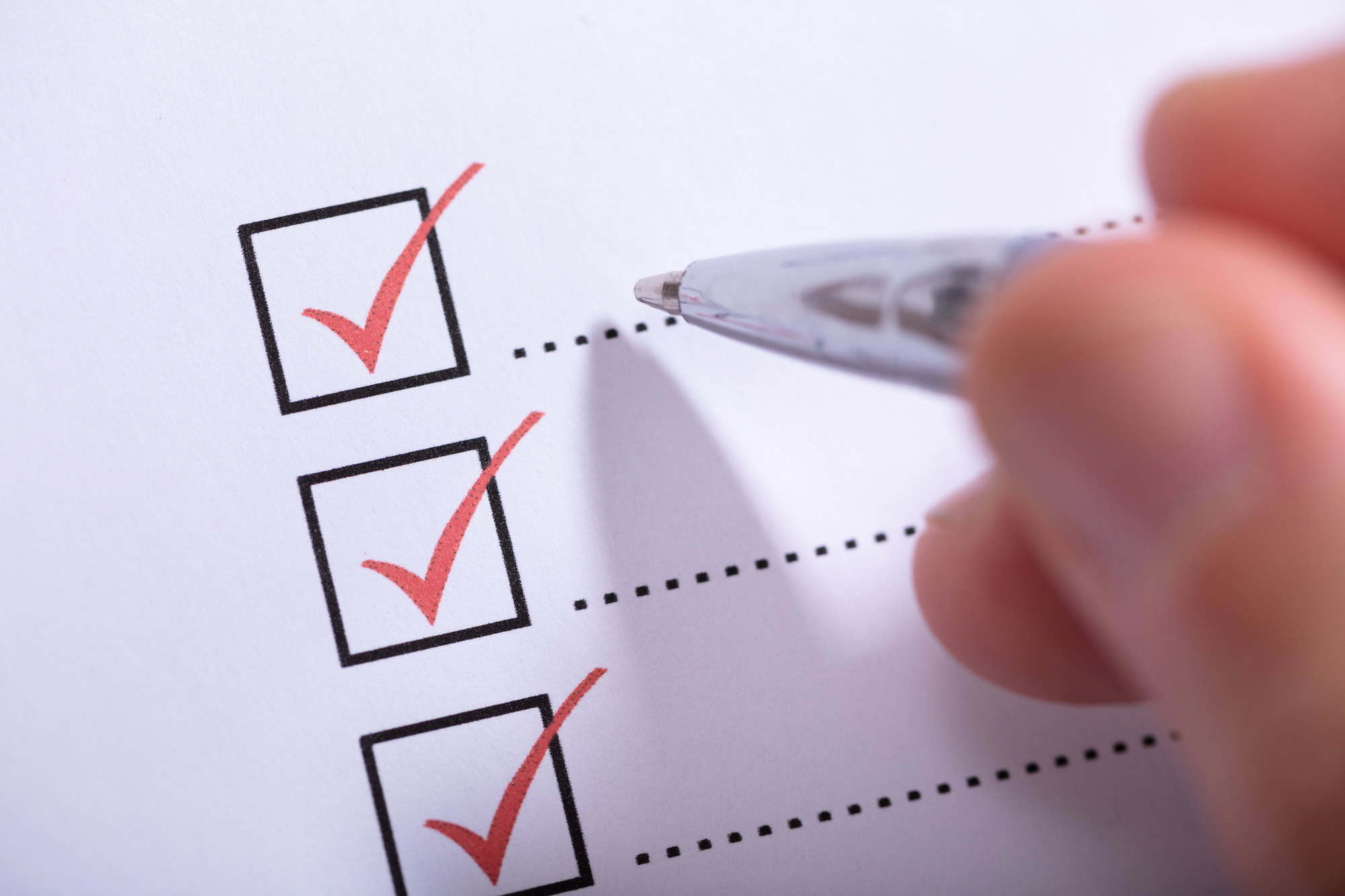 Close-up Of Person's Hand Marking On Checklist With Pen