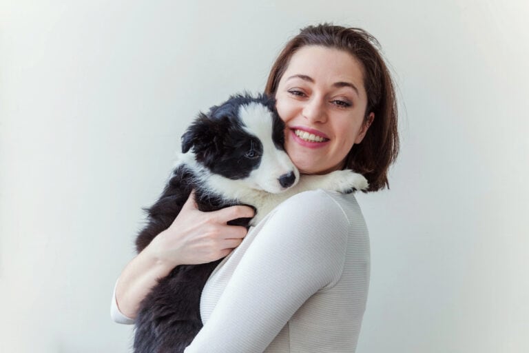 Smiling young attractive woman embracing huging cute puppy