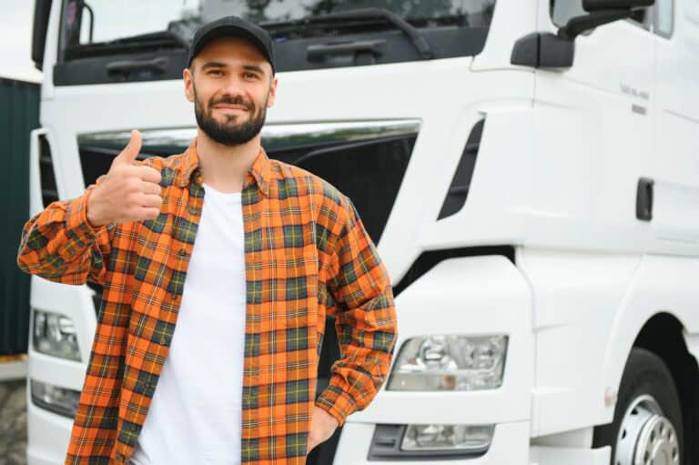 Portrait of young bearded trucker standing by his truck vehicle. Transportation service. Truck driver job.