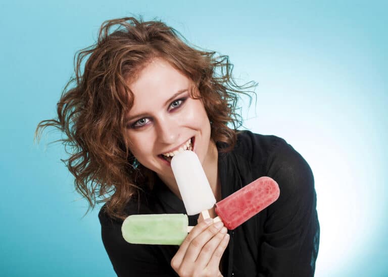 Beautiful girl holding three popsicles and smiling