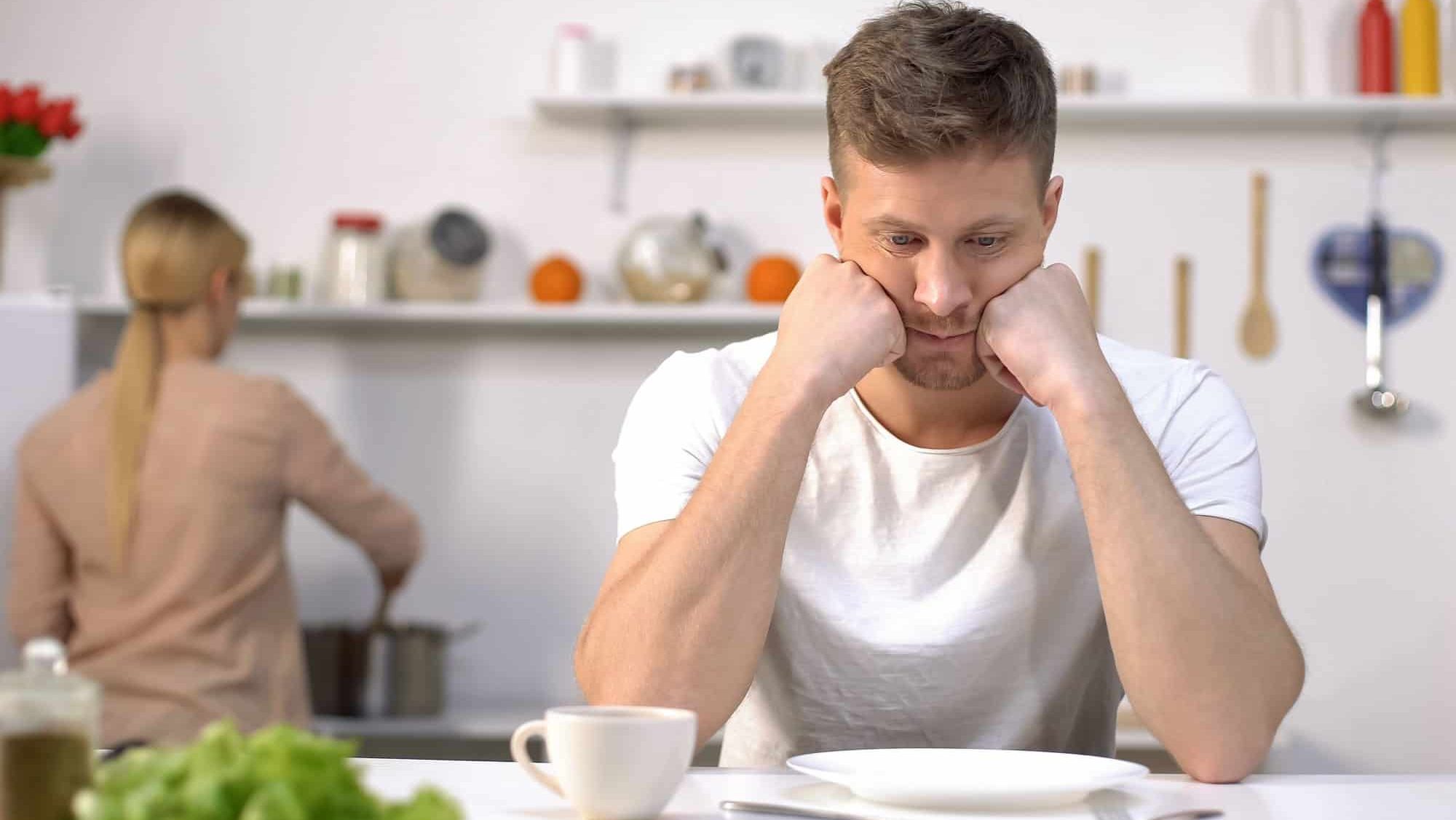 Upset hungry man waiting for dinner, wife cooking on background, divorce risk