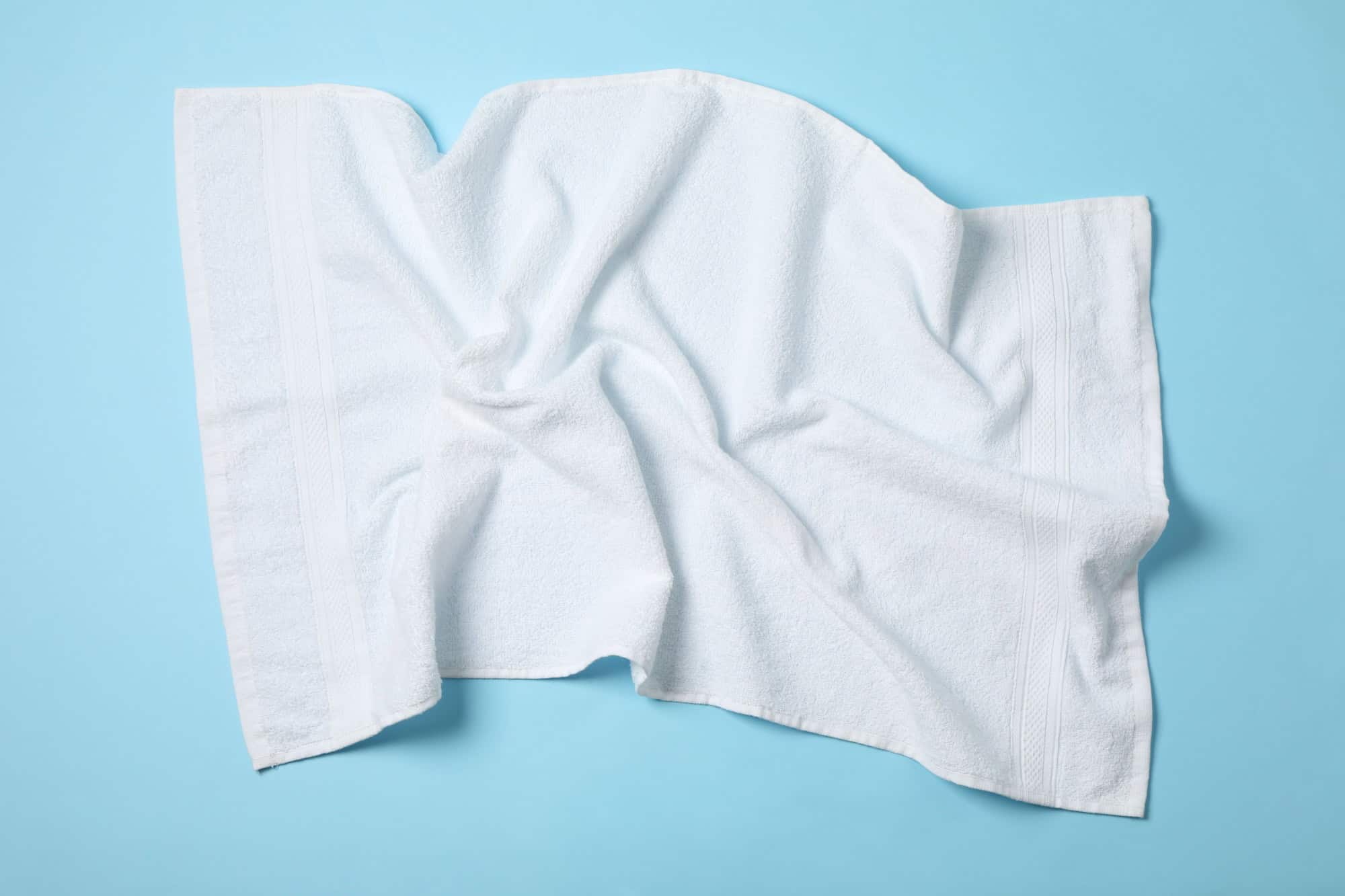 White crumpled towels on blue background, top viewWhite crumpled towels on blue background, top view