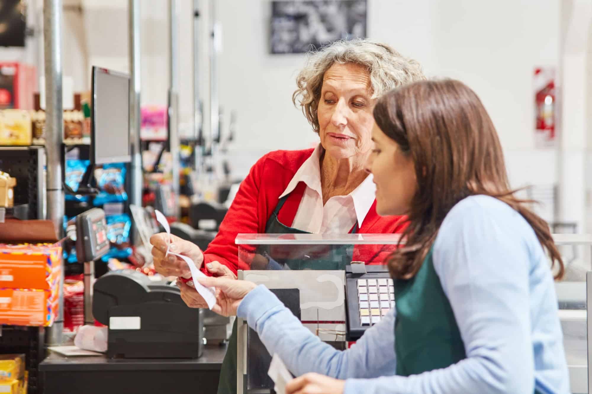 Mature customer and cashier together check a receipt in the supermarket