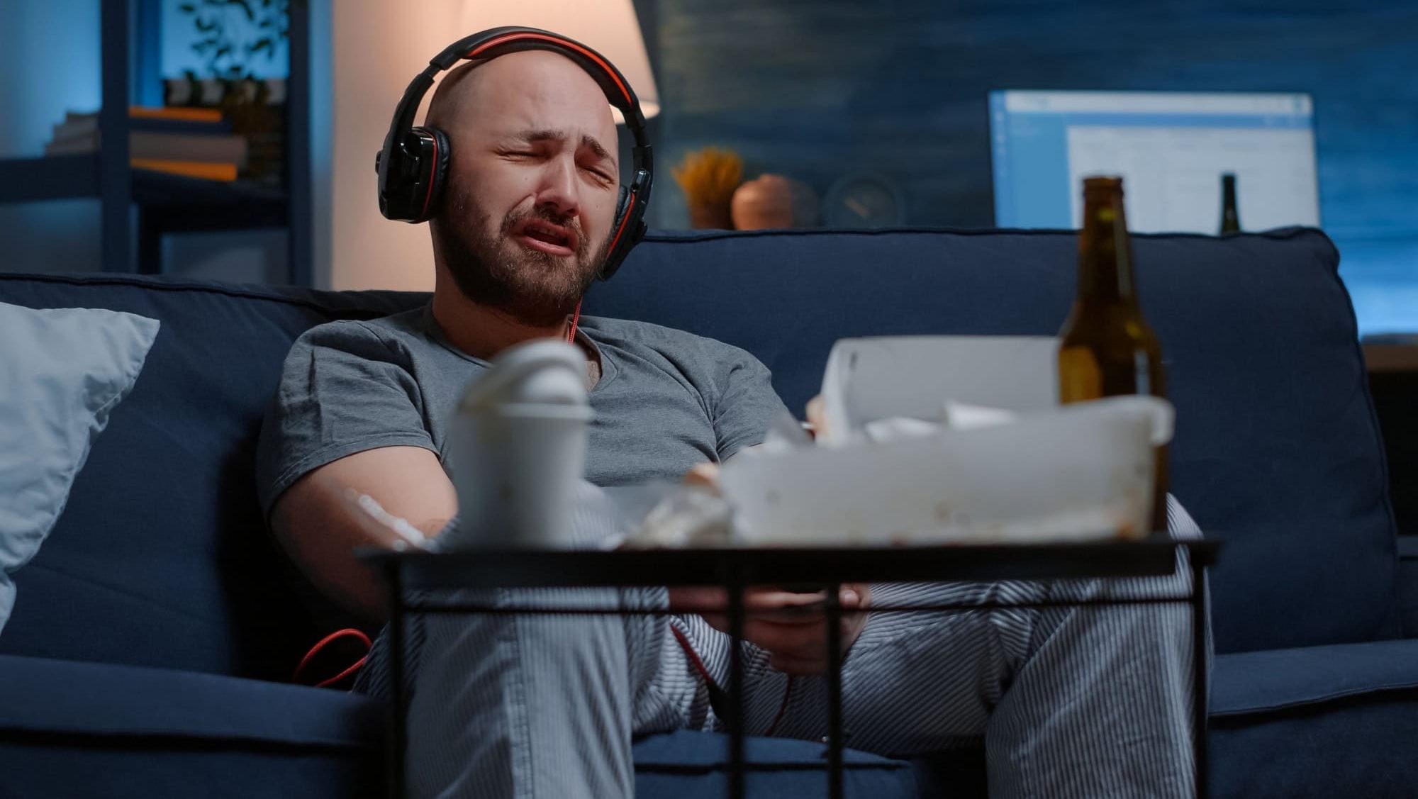 Hopeless depressed man listening sad music at headphones, sitting alone frustrated, stressed on sofa feeling emotionally unstable, lonely desperate, vulnerable suffering from anxiety, chronic disease