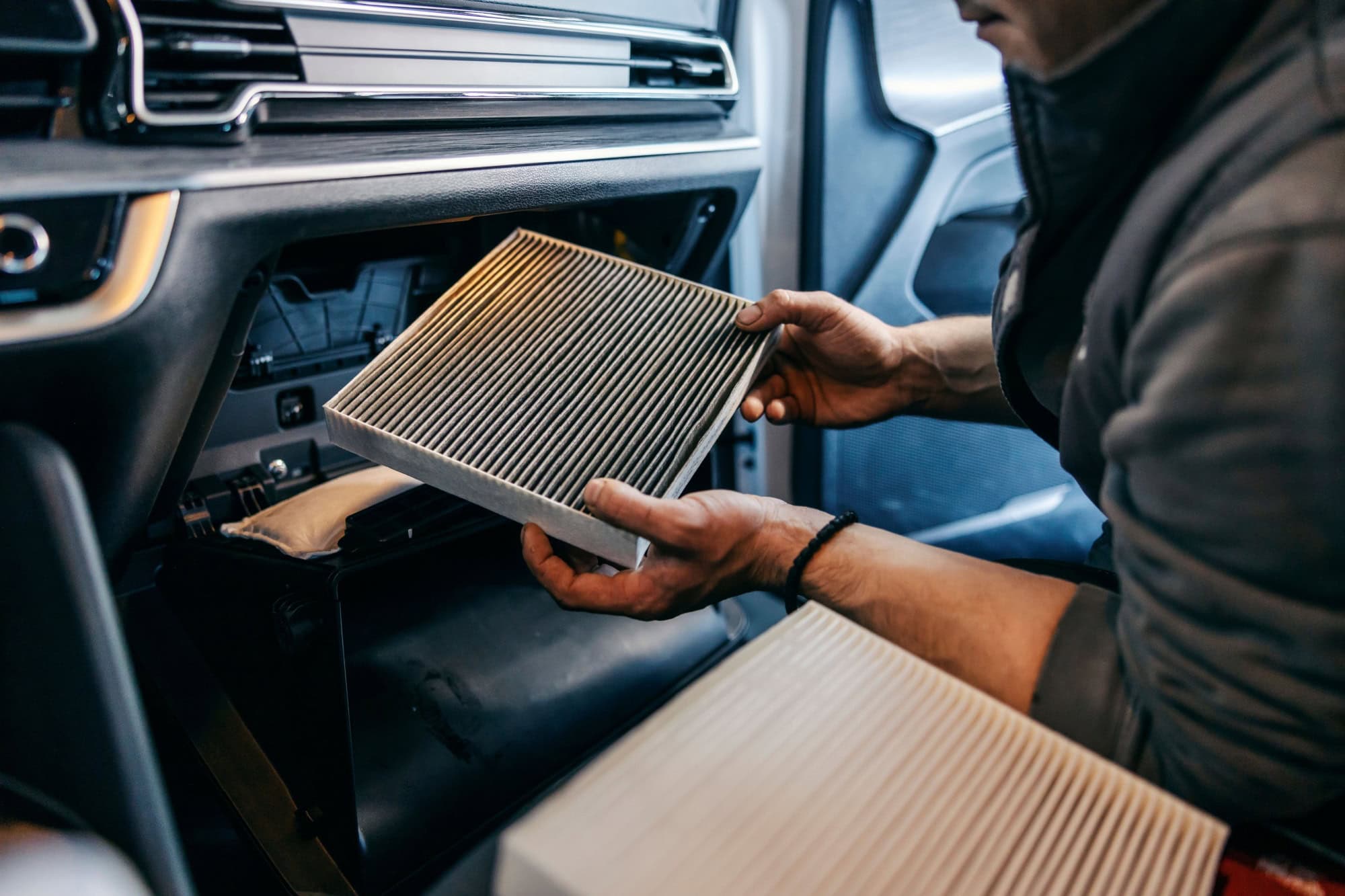Close up picture of a mechanic changing air filters old for new one in a car.