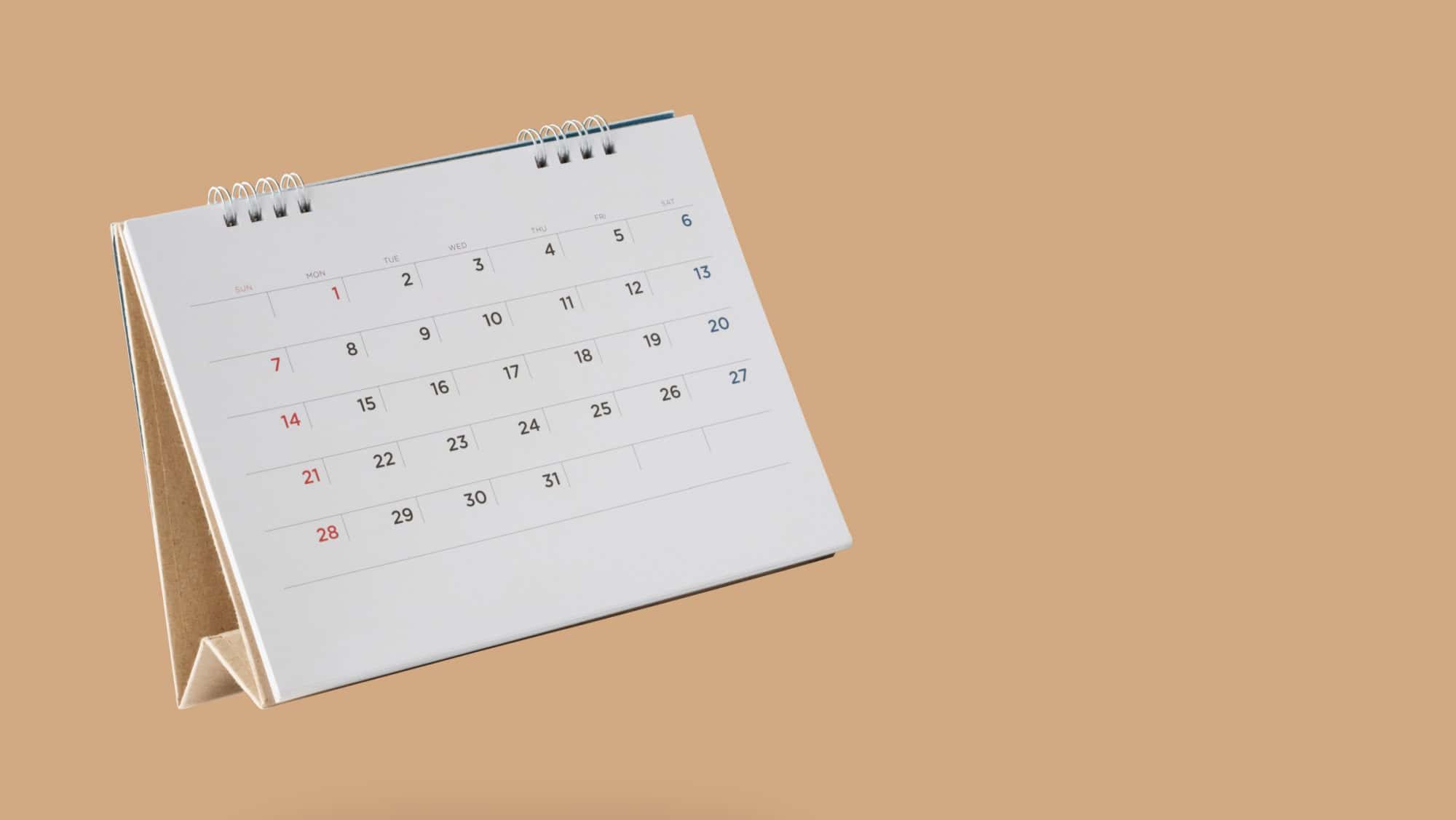 White paper desk calendar flipping page isolated on brown background