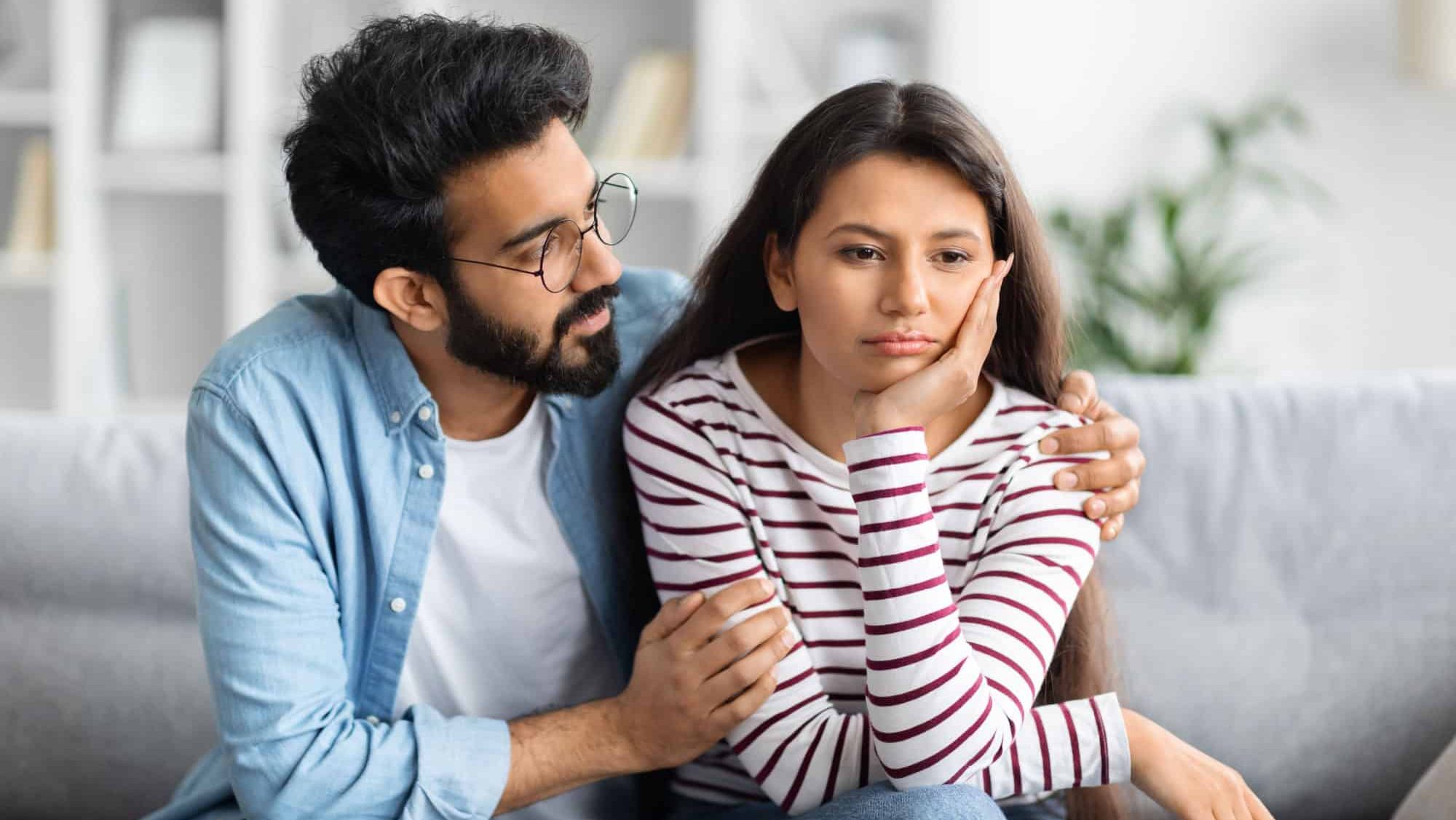 Compassionate eastern husband giving comfort, support to upset wife, holding shoulders, speaking expressing empathy. Man feeling guilty, asking girlfriend to forgive. Relationship, compassion concept